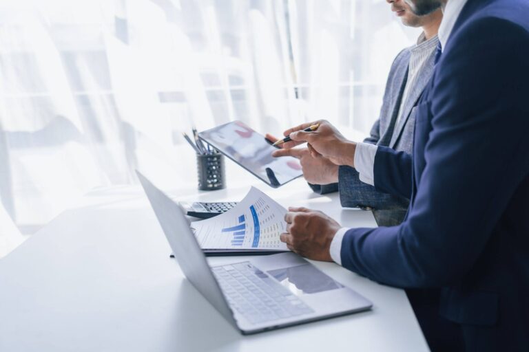 Business professionals reviewing property performance reports and charts on a laptop during a meeting.